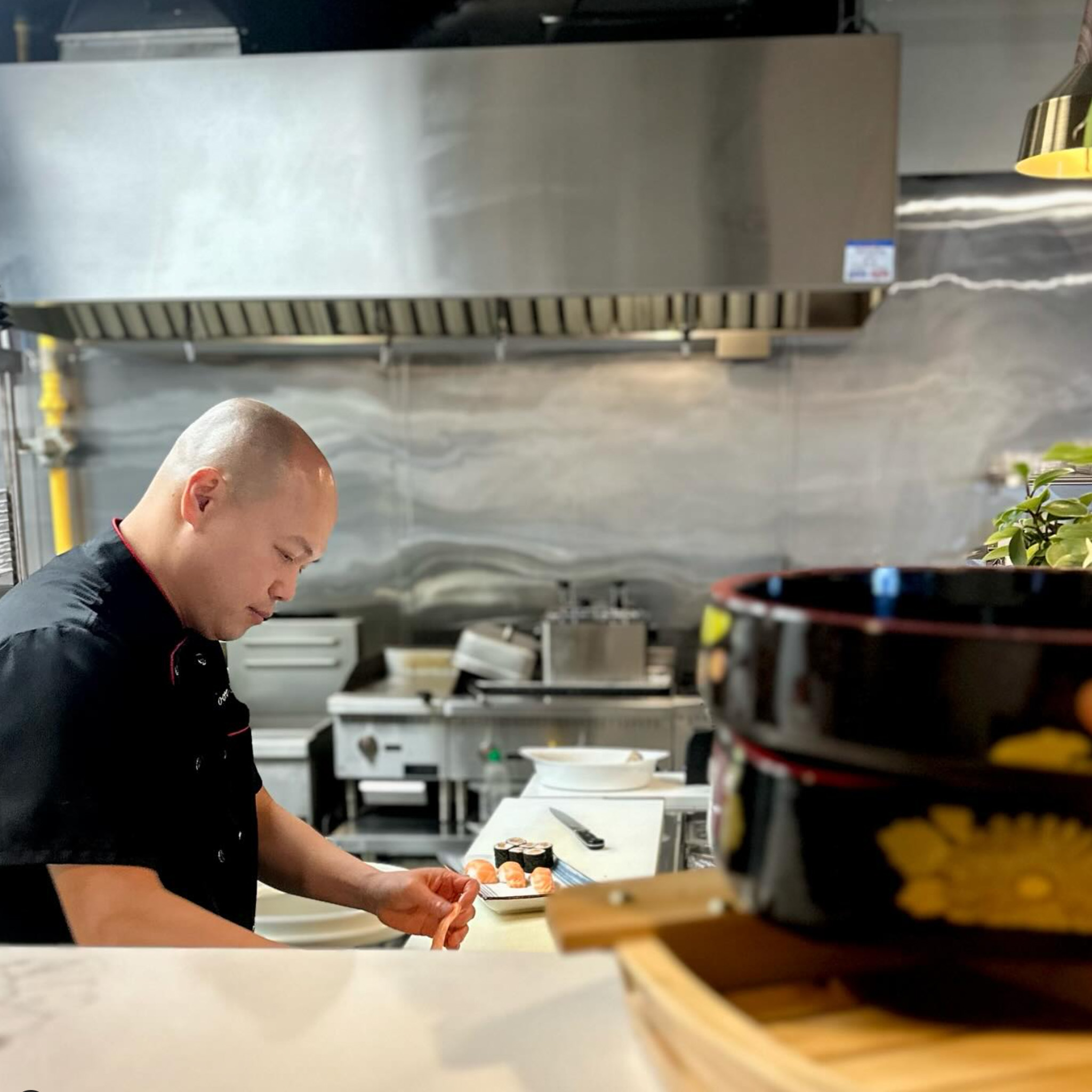 Chef at Moore Sushi carefully assembles sushi in the kitchen.